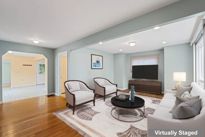 Virtually staged living room with digitally added sofas, armchairs, coffee table and television.