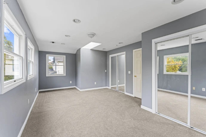Unfurnished residential room with gray walls, carpeted floor, recessed lighting and mirrored closet doors.