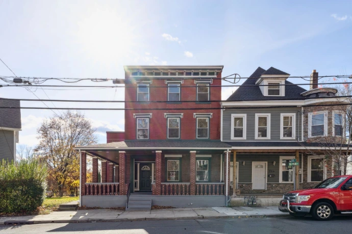 Real estate photography in Warren County, NJ, showing a traditional multi-family residential building with a brick facade and covered front porch.